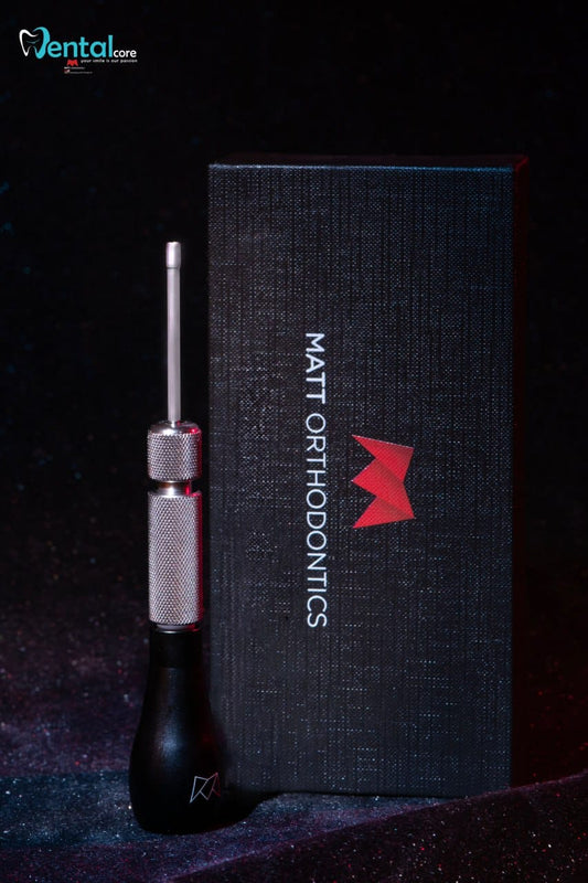 A dental tool with a black handle and silver metal shaft stands in front of a tall black box labeled 'MATT ORTHODONICS' with a red logo, on a dark background. A 'Dental core' watermark appears in the top left
Matt Orthodontics stainless steel mini implant screwdriver with large or small black handle corner.