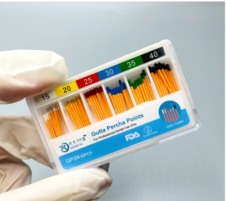 Pack of dental gutta percha points held by a gloved hand against a light gray background